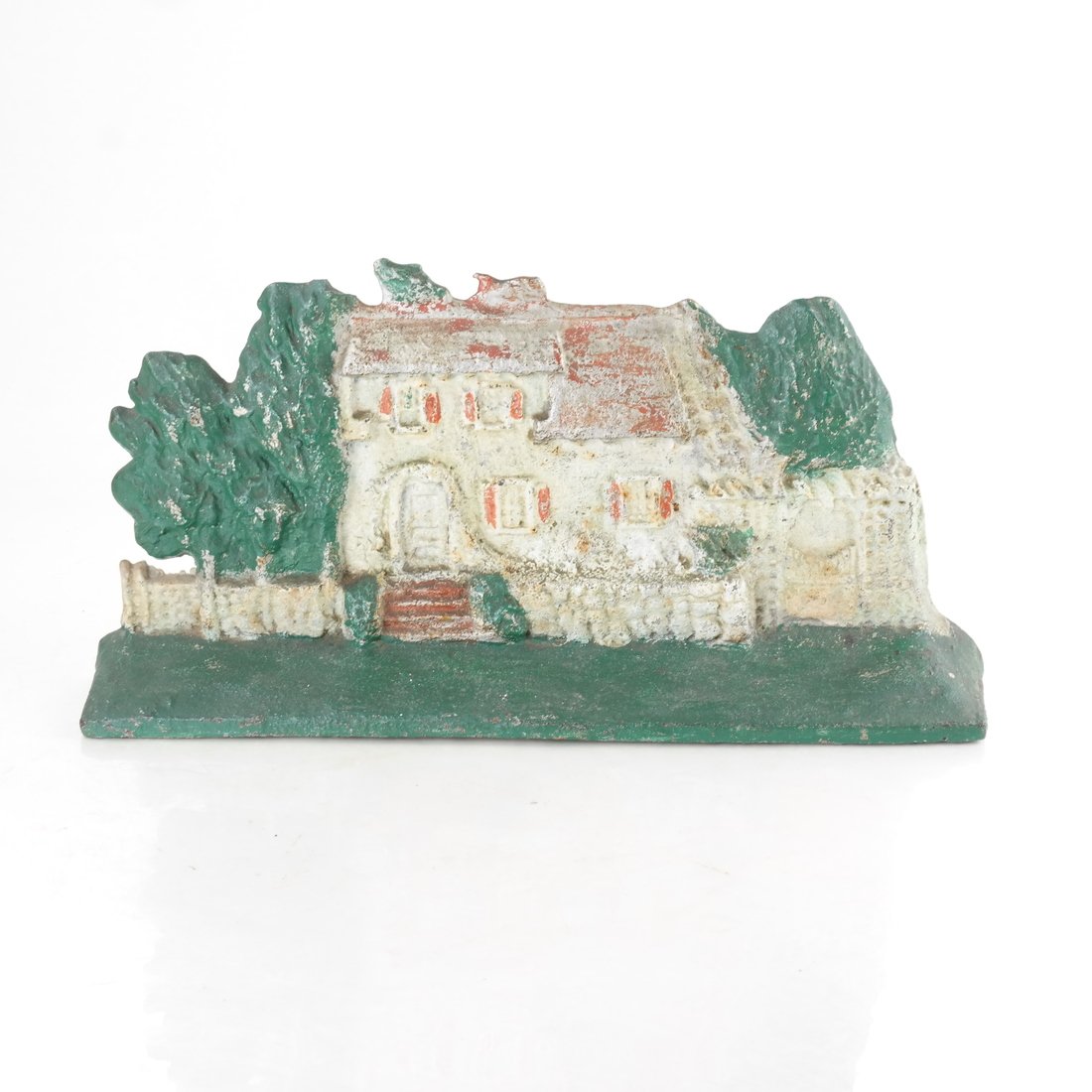 Painted Cast Iron House Doorstop: Modeled and painted as a house set within a rock wall and garden, h: 6 1/8in., w: 12 1/2in.