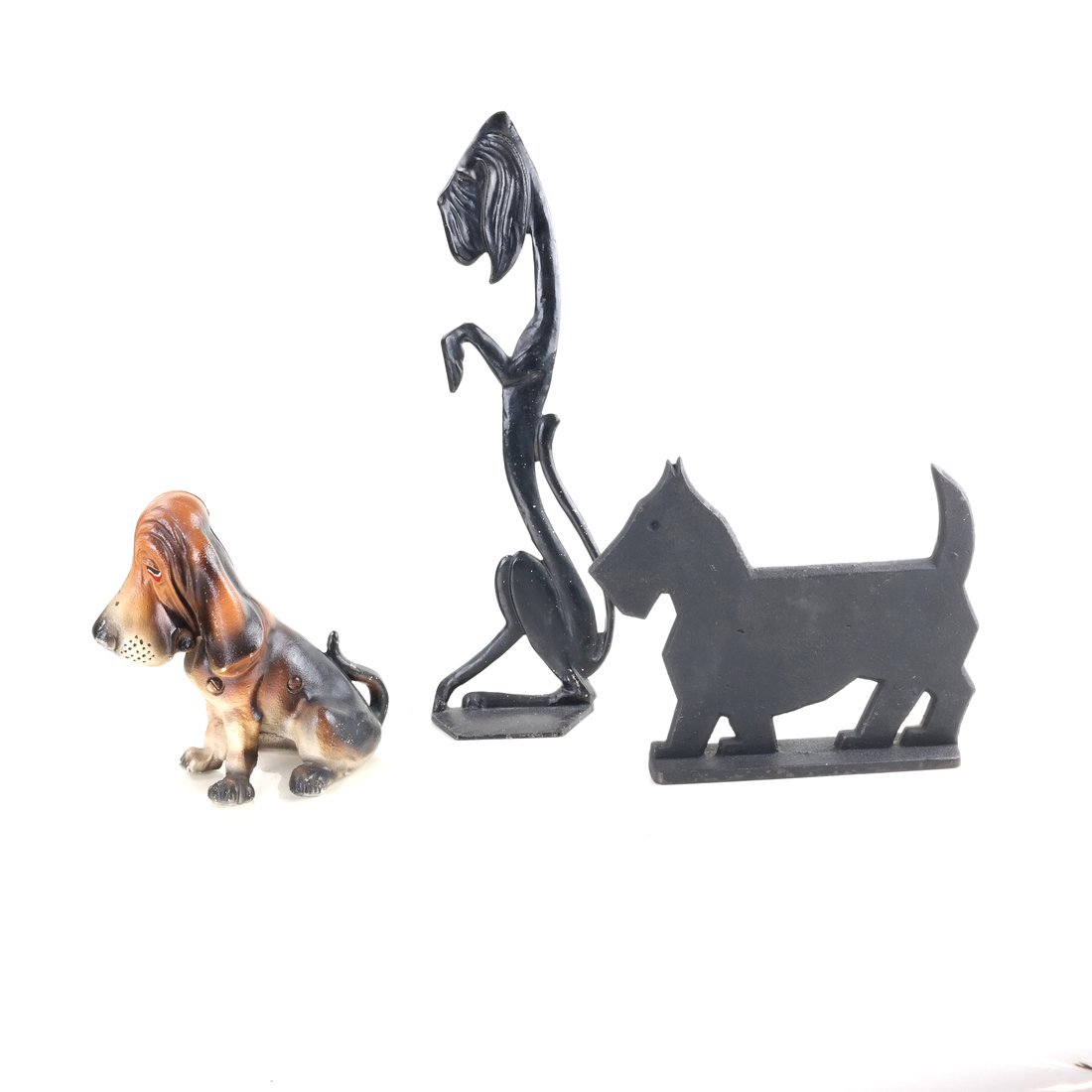 Three Cast Iron Dogs: Comprising: a stylized figure of a seated bloodhound by Spencer, a painted hollow-cast, full-bodied figure of a seated bloodhound, and a doorstop modeled as a silhouette of a Scottie, [Sizes from 15 3