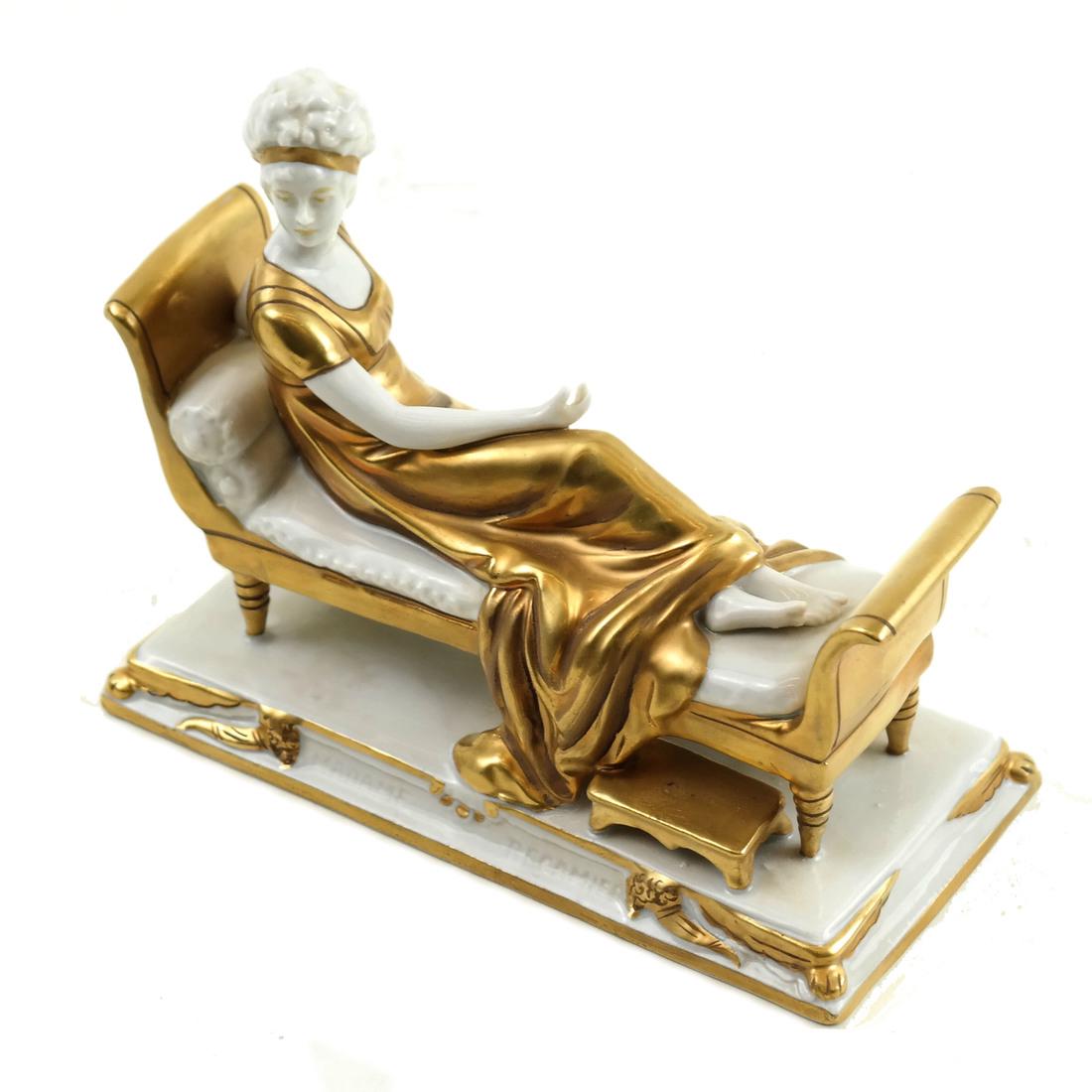 Porcelain Reclining Female Figure: Parcel gilt porcelain figure modeled as a woman reclining on a daybed. [4 1/2" H x 5 1/4" W x 2 1/2" D].