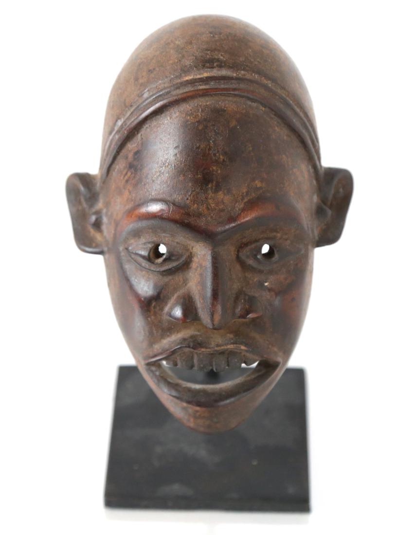 African Head of a Man: Finely carved and polished rendering of the face of a man.[Mask: 6 1/2" H x 4 1/4" W x 4 1/4" D; On stand: 7" H].
