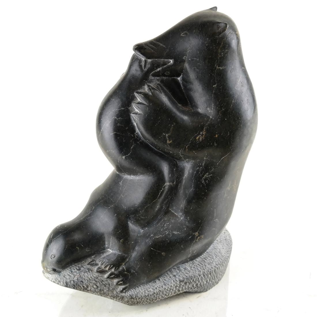 Canadian Inuit Sculpture: Modeled as a bear seated eating a seal. [10 3/4" H x 8" W x 3 3/4" D]. Scratches and marks.