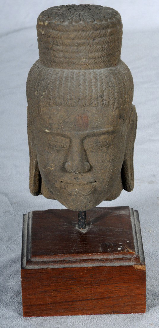 CAMBODIAN CARVED STONE HEAD WITH A CIRCULAR HAT. : CAMBODIAN CARVED STONE HEAD WITH A CIRCULAR HAT. WOOD BASE. 6" H X 3 1/4" W.