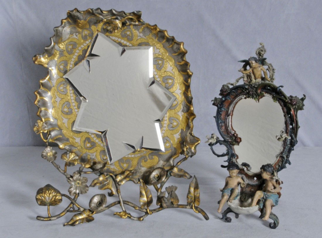 2 METAL EASEL BACK TABLE MIRRORS. ONE IS GILT & S: 2 METAL EASEL BACK TABLE MIRRORS. ONE IS GILT & SILVER PLATED, AND THE OTHER IS A LXV STYLE W/ CUPIDS. 18 1/2" H X 15" W & 15" H X 8" W.
