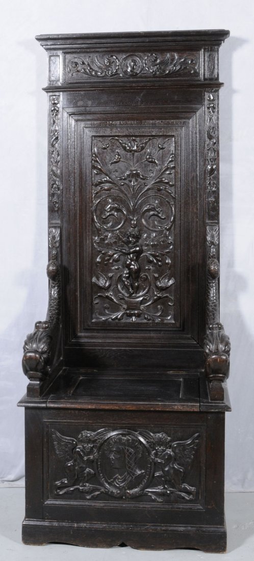 19TH C. CARVED OAK HALL SEAT W/ A HIGH BACK. CENT: 19TH C. CARVED OAK HALL SEAT W/ A HIGH BACK. CENTER PANEL CARVED RELIEF DECORATION OF A FIGURE W/ A BIRD. DRAGON HEADS & FLOWERS. DOLPHIN ARMS. FRONT LOWER PANEL HAS 2 WINGED CUPIDS & BUST DECORATION.