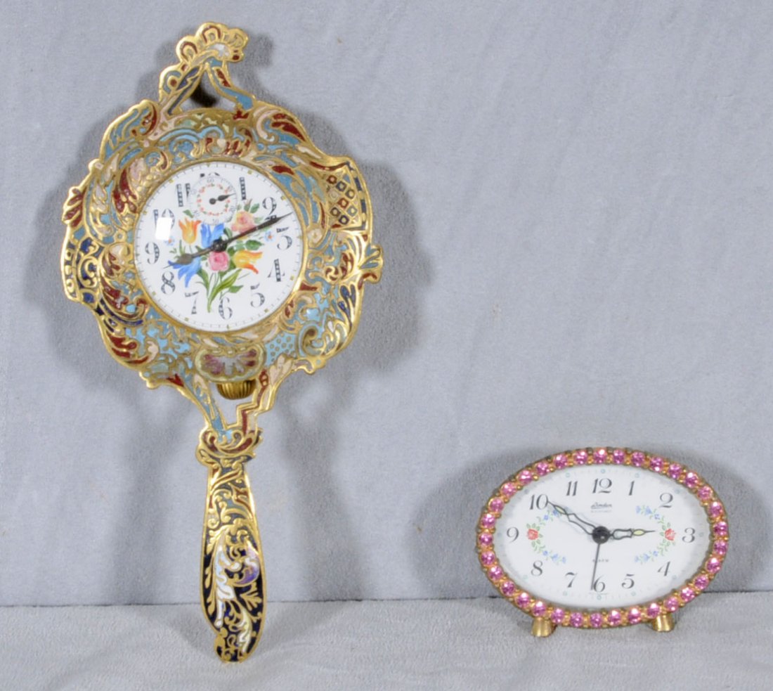 2 CLOCKS. ONE IS A CHAMPLEVE SPOON SHAPED CLOCK AN: 2 CLOCKS. ONE IS A CHAMPLEVE SPOON SHAPED CLOCK AND THE OTHER IS AN OVAL PINK RHINESTONE FRAMED SMALL CLOCK. 8 1/8" H X 4" W & 2 1/2" H X 3 1/4" W. (TK)