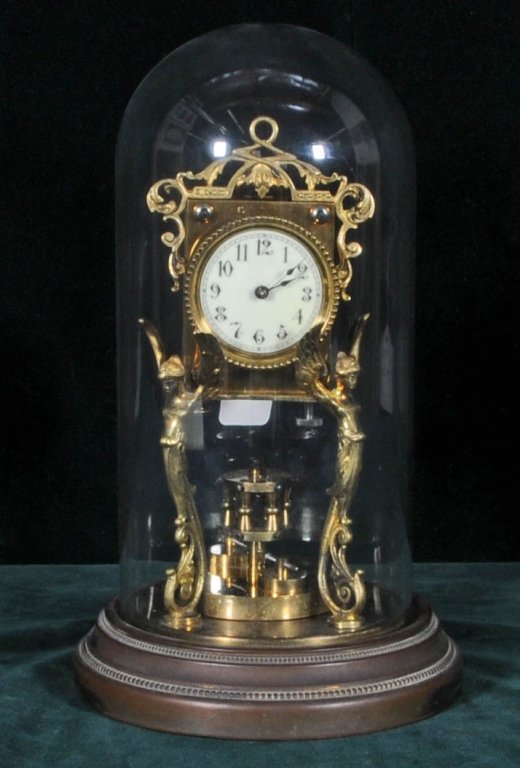 ANTIQUE GILT METAL CLOCK. WINGED FEMALE FIGURAL SUPPORT: ANTIQUE GILT METAL CLOCK. WINGED FEMALE FIGURAL SUPPORTS. ROUND PENDULUM. ROUND METAL BASE WITH GLASS DOME. GOOD. 10 1/2" H X 7 1/2" DIA. BASE.