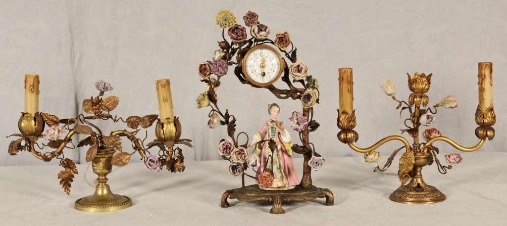 3 PIECE BRONZE & PORCELAIN BOUDOIR CLOCK SET. CONS: 3 PIECE BRONZE & PORCELAIN BOUDOIR CLOCK SET. CONSISTING OF A SMALL ROUND CLOCK WITH A FEMALE PORCELAIN FIGURE UNDERNEATH THE CLOCK. PR. 2 LIGHT SMALL CANDLEABRA. 3 PIECES DECORATED WITH PORCELAIN FLO