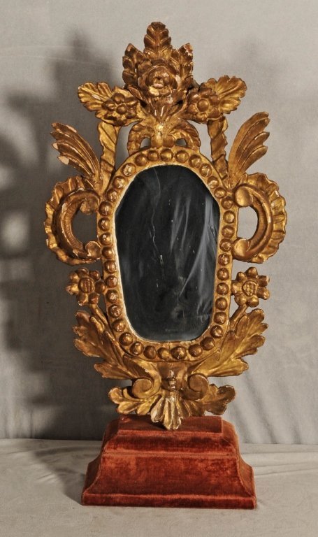ANTIQUE ITALIAN TABLE TOP GILT MIRROR. OPENWORK FLOR: ANTIQUE ITALIAN TABLE TOP GILT MIRROR. OPENWORK FLORAL AND SCROLL DESIGN FRAME. RED VELVET STAND. SOME CHIPS. 28"H X 14" W X 5" D.