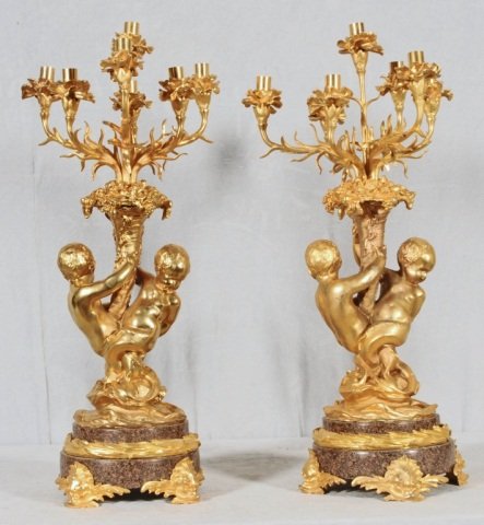 PAIR OF BRONZE 7 LIGHT CANDELABRAS. 2 FIGURES OF: PAIR OF BRONZE 7 LIGHT CANDELABRAS. 2 FIGURES OF CUPIDS ARE AROUND THE TREE TRUNKS AND SUPPORTING THE SCROLLED CANDLE HOLDERS. MARBLE AND BRONZE BASES. GOOD. 28 1/2" H X 10" DIA.