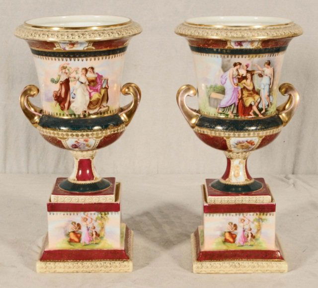PAIR OF ROYAL VIENNA STYLE URNS. FLAIRED URNS WITH: PAIR OF ROYAL VIENNA STYLE URNS. FLAIRED URNS WITH FIGURAL DECORATION. RED, GREEN AND GOLD BANDS. BEEHIVE MARK OVER THE GLAZE. ONE AS IS. 16" H X 8" DIA.