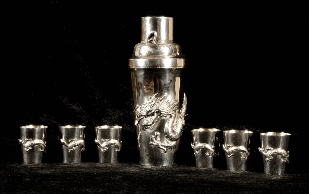 7 PC. CHINESE SILVER COCKTAIL SET. CONSISTING OF A: 7 PC. CHINESE SILVER COCKTAIL SET. CONSISTING OF A COCKTAIL SHAKER & 6 CUPS. DRAGON DECORATION ON THE SHAKER. LIZARD & SPIDER DECORATION ON THE CUPS. 23.40 TROY OZS. SHAKER BOTTOM IS LOOSE. 8 1/2" H X
