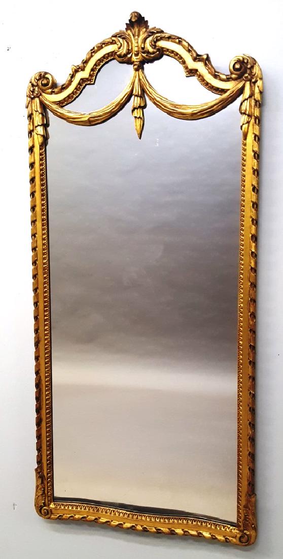 C 1920's Gilt Wood carved mirror in Neoclassical Taste: C 1920's Gilt Wood carved mirror in Neoclassical Taste - with a ribbon-bound surround and a serpentine crest supporting giltwood swags. Hgt 65" w 30". Good original gilt condition with some light wear