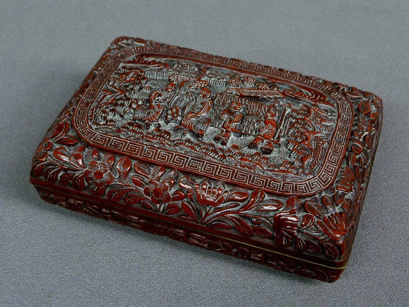 19th/Early 20th Century HEAVILY CARVED CINNABAR BOX: 19th/Early 20th Century HEAVILY CARVED CINNABAR BOX with BRASS TRIM signed on base, with garden scene in dark red lacquer, L 5 .75" W 4" Hgt 2"- good condition