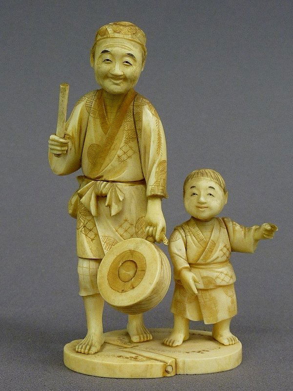 CARVED IVORY FIGURE OF MAN DRUMMING WITH BOY - hei: CARVED IVORY FIGURE OF MAN DRUMMING WITH BOY - height 5.5" width 3" , signed on base - good condition