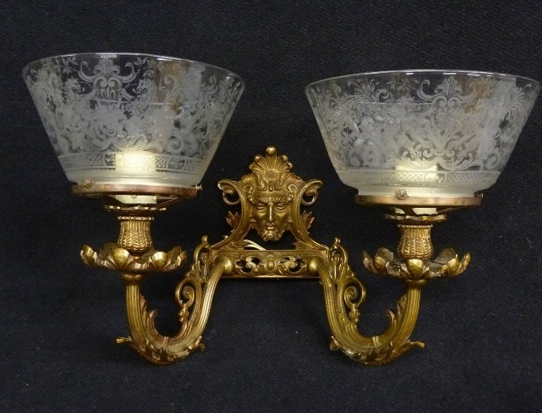 Circa 1910 Bronze Two Arm Wall Sconce with Man's Face a: Circa 1910 Bronze Two Arm Wall Sconce with Man's Face and Antique Shades with Lions - width 17" height 11" - good rewired condition