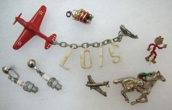 6 Pc. Vtg. Airplane, Santa, Race Horse Etc. Pins: Inc. 6/8" Santa Charm, 1 1/2" Red Lucite Airplane Duet Pin w/ LOIS Charm's, 1 3/4" Race Horse Pin, 7/8" Airplane Pin & Spark Plug Earrings.