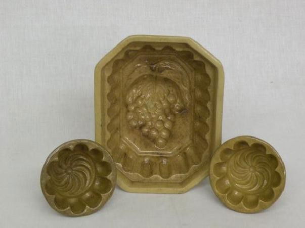 3 yelloware molds: all ca. 1850-1875, large rectangular mold with cluster grape design, 8 ¼"x 6 ½"x 3 ¾"; pair of round molds with pin wheel designs, 3 ¾"d, 2 ¼"h;