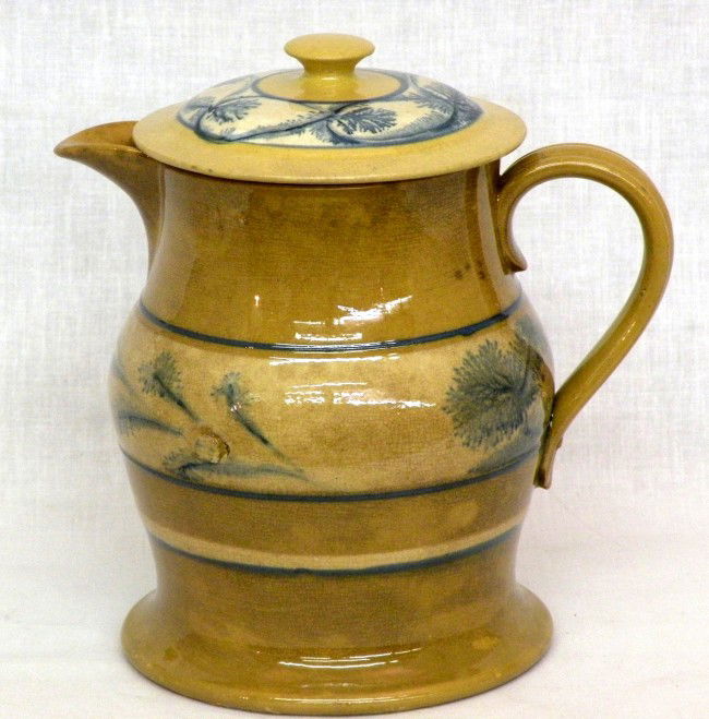 Yelloware mocha covered pitcher: ca. 1870; bulbous pitcher with blue & white slip rings, blue seaweed band, molded strap handle & flared base, attributed to Ohio;