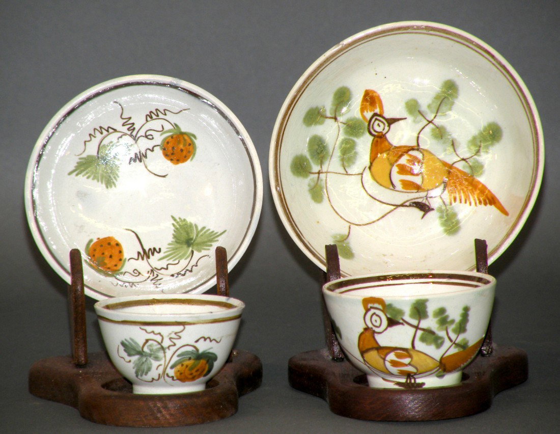 2 Leed's type child's cups & saucers: ca. 1820; 1 set with strawberry design in brown, green & orange, cup 1 7/8"d, 1 1/8"h, saucer 3 1/8"d, 7/8"h; 1 set with peafowl design in brown, green, orange & yellow, cup 2 1/8"d, 1 ¼"h, saucer 3 