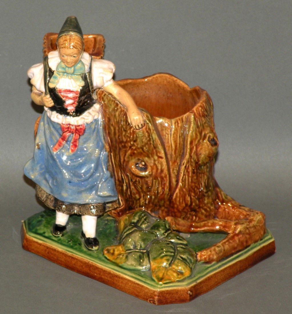 Figural cigar stand: ca. 1890; polychromal earthenware with woman resting by a tree stump with woman's backpack basket and tree stump as the open receptacles,