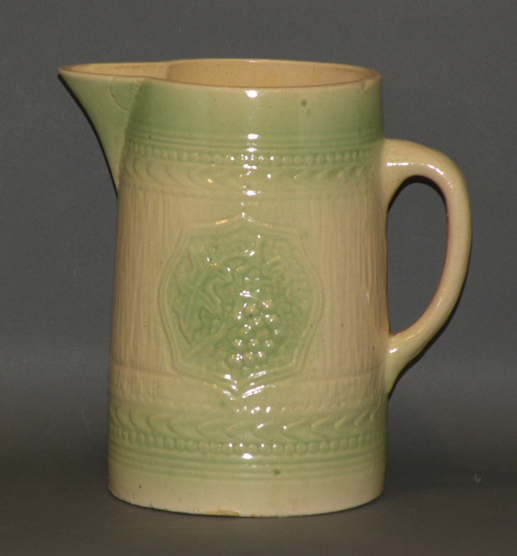 Yelloware milk pitcher: ca. 1900; with two molded grapes and vine panels, molded top and bottom borders and green wash;