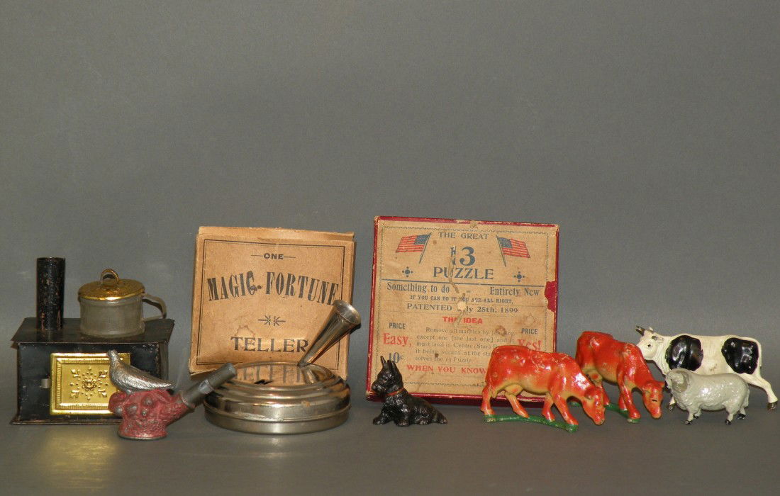 4 primitives & 5 animals: ca. 1900; German tin doll house stove; lead dove bird whistle; tin magic fortune teller with box; thirteen puzzle with Bennington marbles; two cast gray iron cows; one slush Timpo cow; small Hubley ca