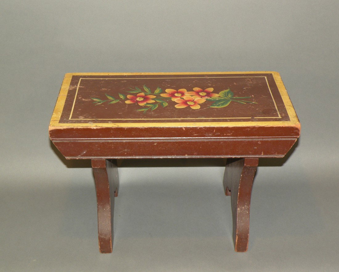 Paint decorated footstool: ca. 1890-1930; cutout legs with brown ground, yellow striping and a floral spray decoration, 15 1/8"x 8 3/8"x 9 ¾";