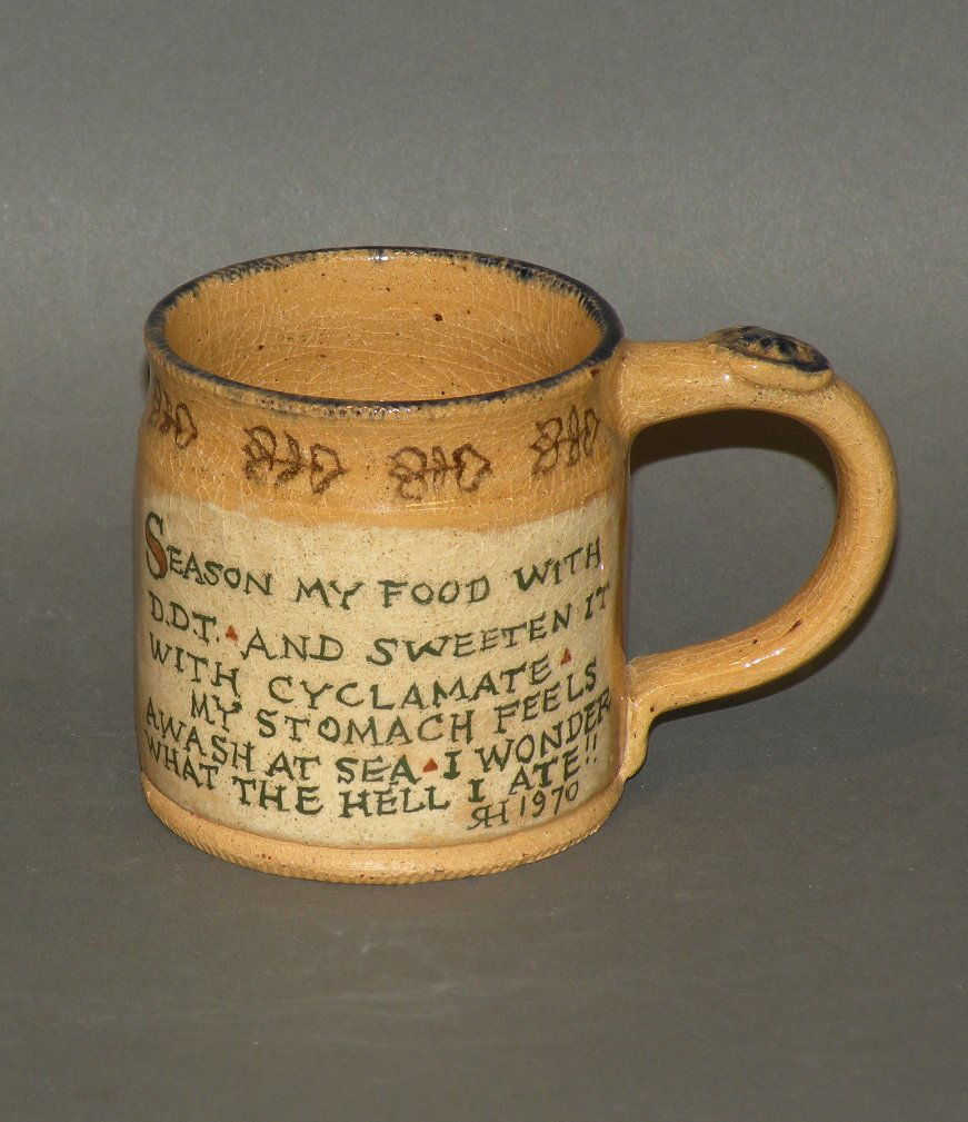 Left Handed Russell Henry small mug: ca. 1970; earthenware with four lines of prose, coggled foot and rim with tulip and heart motif, tan body and signed and dated 1/70, 2 7/8”d, 2 7/8”h;