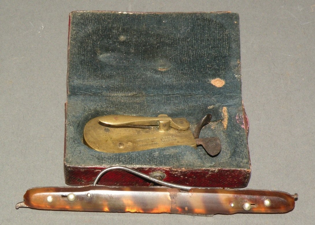 2 medical bleeder tools: ca. 1700-1820; brass house spring operated bleeder by Wiegand & Snowden (Philadelphia, PA) with original leather covered wooden case, 1 ½”x 2 ¾”; tortoise shell lance with 2 locking blades marke