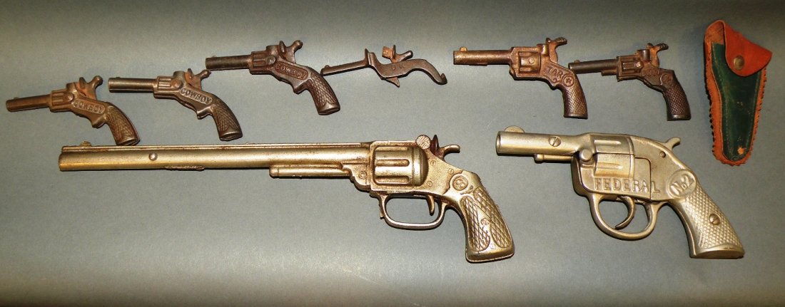Lot of 8 cap guns & 1 holster: ca. 1910-30; Kilgore Federal #2 cap gun, 6”; Kenton “Long Tom” cap gun, 11 ½”; 3 cowboy, 1 O.K., 1 star and 1 buck miniature cap guns with 1 holster, 3”- 3 ½”;
