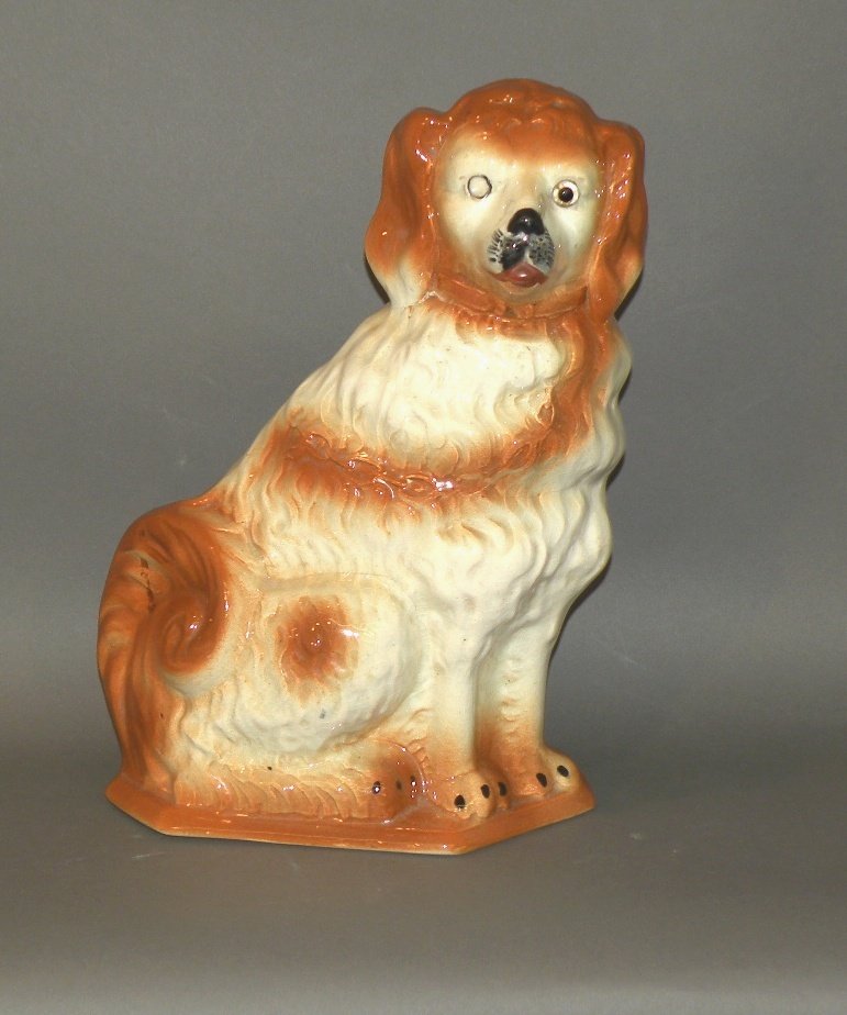 Staffordshire seated spaniel: ca. 1890; late Staffordshire dog having over all burnt sienna detailing with black and red touches, applied glass eyes and copper lustre touches on collar, 13”x 5 3/8”x 8 ¾”;