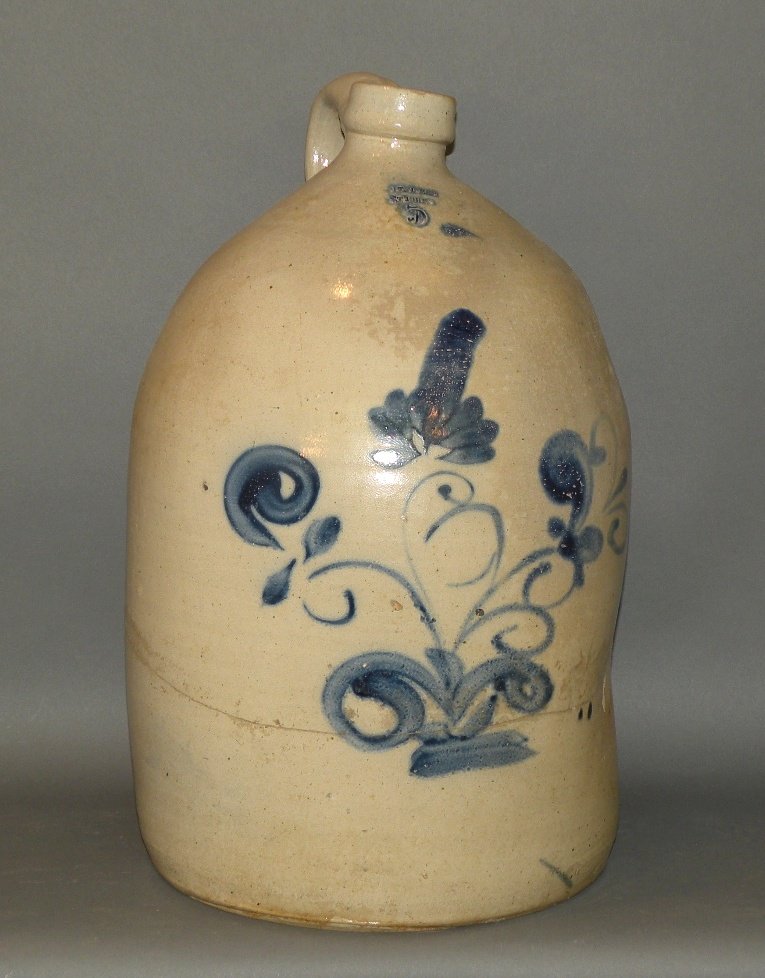 Cobalt decorated 5 gallon stoneware jug: ca. 1880; salt glazed with large brushed floral cobalt decoration and impressed “J.T. Hagen, St. Johns 5” (St. Johns, Quebec) with Albany slip glaze interior, 12 ¼”d, 18 ¼”h;