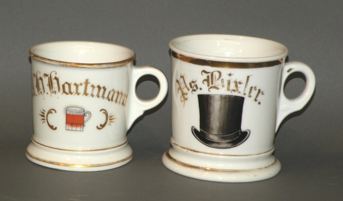 2 occupational shaving mugs: ca. 1900; beer mug decorated with gilt name “A H Hartmann” and porcelain body, 3 ¼”d, 3 3/8”h; top hat decoration with gilt name “P S Bixler” and porcelain body ink stamped “D & Co”, 
