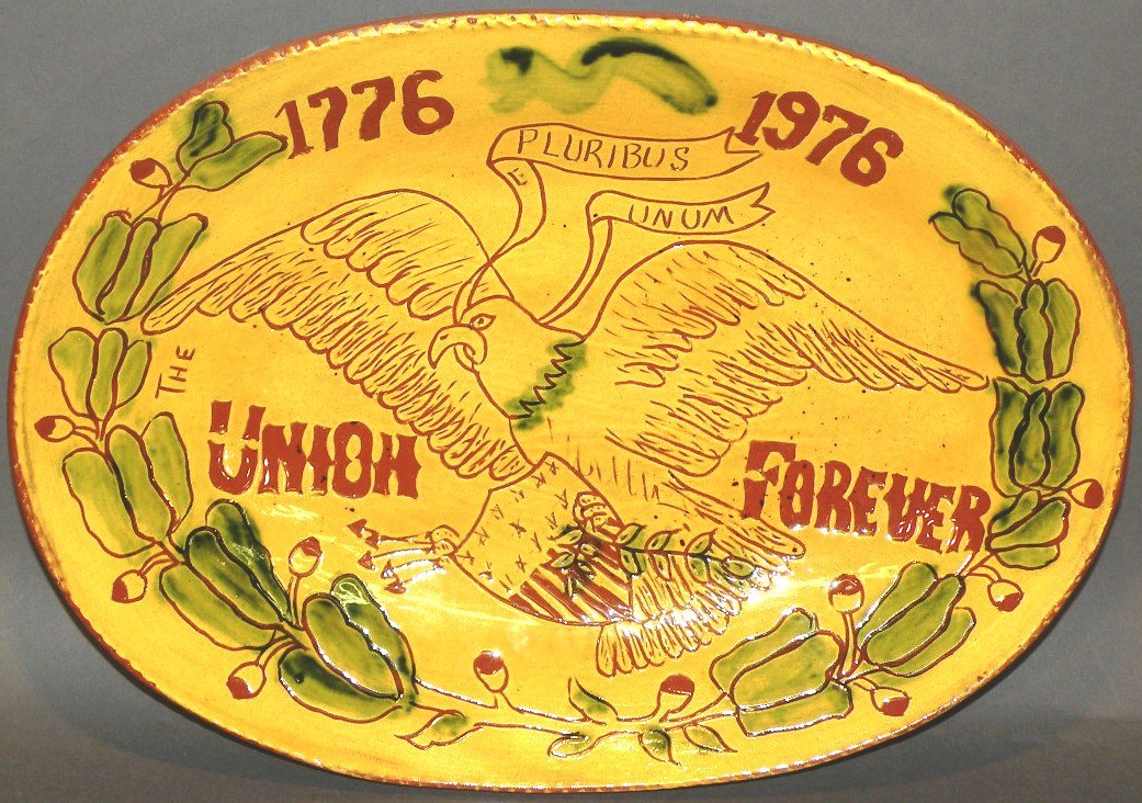 Breininger sgraffito redware loaf dish: ca. 1975; with bicentennial design of spread eagle and shield with “Pluribus Unum” ribbon and “1776-1976 the Union Forever” legend, flower, bud and leaf border, yellow overcoat with green spon