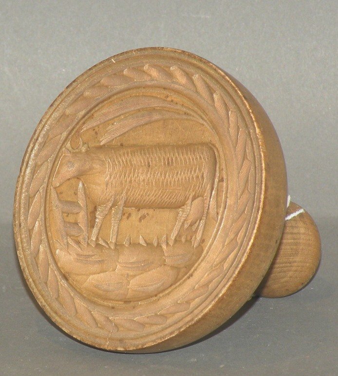 Cow butter print: ca. 1830-70; finely carved cow standing by a hay manger with a shaped handle, 3 ¾”d, 3 7/8”h;