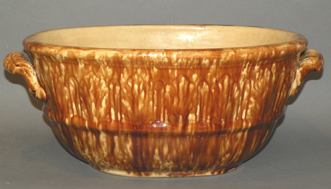 Rockingham bowl: ca. 1880; earthenware with molded palmette leaf design on shoulder, open ornate molded handles and a waist band (Provenance: ex-Clyde Youtz collection) 6”x 9 7/8”x 13 ½”;