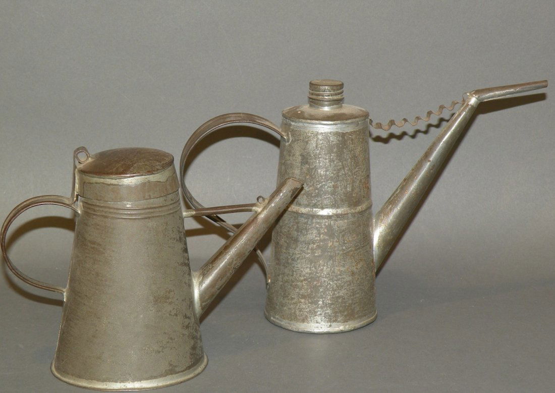 2 tin lamp fillers: ca. 1830-1910; early form model with braced spout, hinged lid and strap handles, 5 ½”; later form with strap braced two-part spout, screw cap and strap handles, 6 ½”;