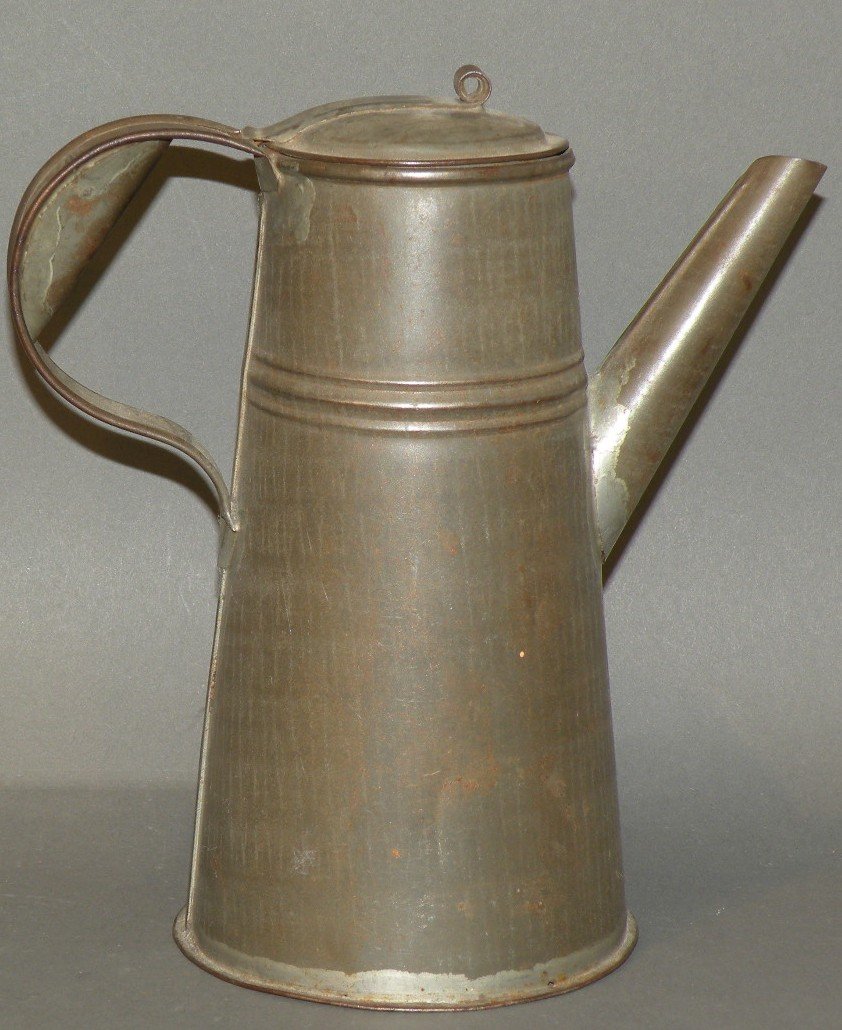 Tin chocolate pot: ca. 1830-50; early form tapered cylinder shaped body with braced strap handle and hinged lid with strap and loop knob, 8 ½”;