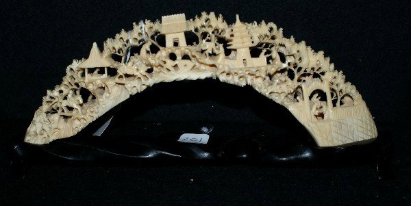 Chinese carved ivory tusk bridge; intricately ca: Chinese carved ivory tusk bridge; intricately carved openwork with figures in a landscape, trees, pavilions and multi-tiered temple on a lacquered wood stand. Ivory length along outer curve: 12"