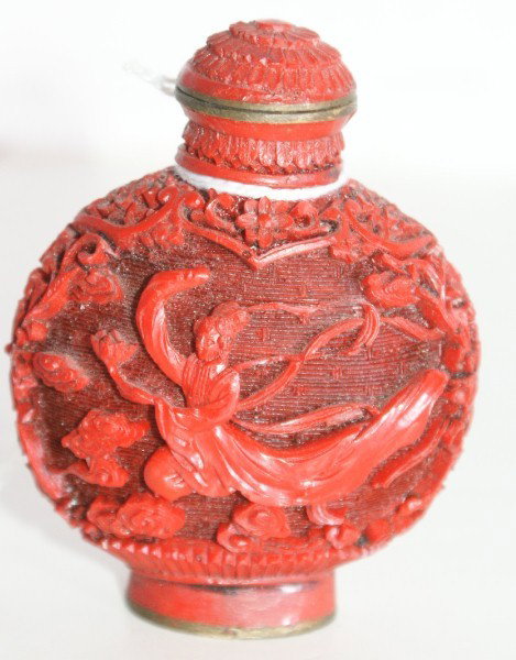 Chinese carved cinnabar on brass snuff bottle carv: Chinese carved cinnabar on brass snuff bottle carved in relief to depict a costumed figure in the clouds. 2 1/2"