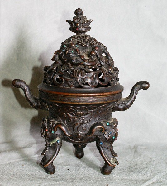 Chinese bronze and jeweled elephant censer.: 19th century or earlier Chinese Bronze tripod censer with inlaid jeweled and bead work supported by three elephant heads with curved trunks forming the legs flanked by elephant head handles. H:8" W:6.