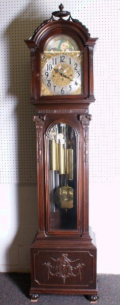 19th C Grandfather clock in a Adam style case with: 19th C Grandfather clock in a Adam style case with rams heads on each side of door and the bottom with carvings of putti and flowers,The face of the clock is brass and painted. Herschede movement -9 t