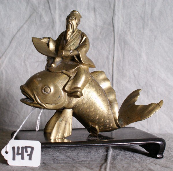 19th C Chinese Bronze figure of a man riding a fis: 19th C Chinese Bronze figure of a man riding a fish on a hardwood stand. H:7.5" L:7" W:4"