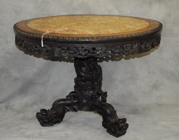 Large 19th C Chinese carved hardwood center table with: Large 19th C Chinese carved hardwood center table with dragon form carved column pedestal raised on claw feet, the top with a inset marble top bordered by heavily carved border of foliage and animals.