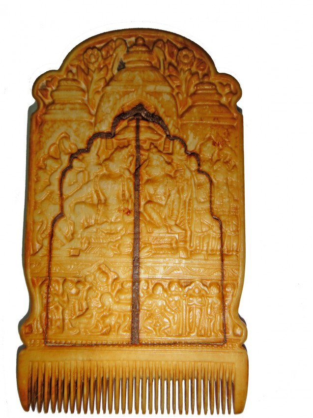 A IVORY COMB EAST INDIAN PROBABLY 17TH CENUTRY: pierced with a central ivory deity in lotus position , between finely carved teeth above and below faced left and gurad toward its right , below engraved human figures in different position and style.