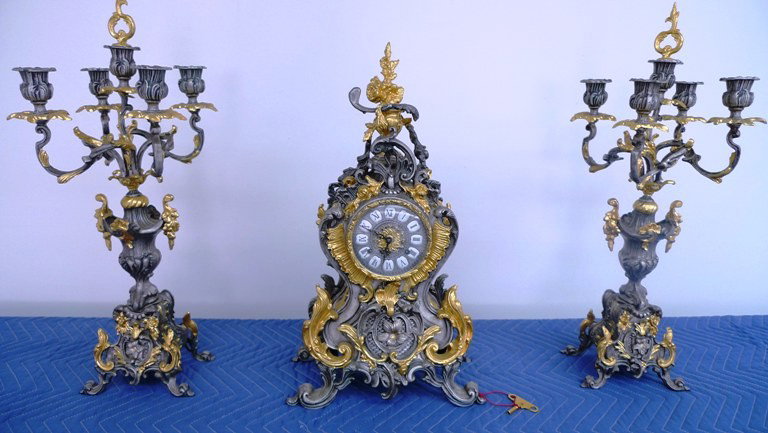Silver Clock and Candelabra set( 3 Pieces) with ke: Silver Clock and Candelabra set( 3 Pieces) with key by Franz Hermel 151-080 movement made in Germany. Signed on the movement by Franz Hermel. Clock 21" tall & the candelabra is 23" tall. Metal.