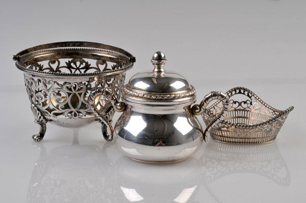 Three silver decorative objects: Tres piezas de plata.Elaboradas en plata 0.800. Azucarera. Base de dulcero en forma de canasta y platito dulcero con diseño calado. Peso total: 538 gr.