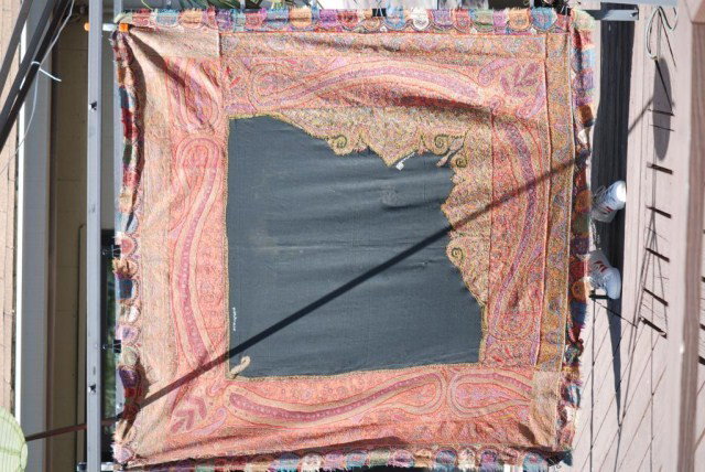 ANTIQUE PAISLEY SHAWL: Antique Paisley Shawl, irregular shaped black center section, stitched to be folded over like a handkerchief, signed in center, damages, minor holes, 71" x 71".