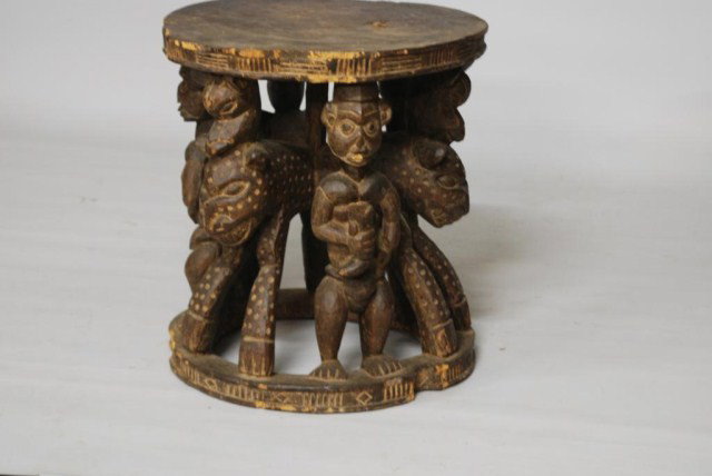 ANTIQUE AFRICAN CENTER TABLE: Antique African Carved Center Table, 6 figures connected to the center column, losses to the edge, roughness and distress to the wood, 24" high x 22-1/2" diameter.