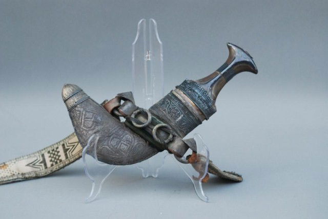 ANTIQUE MIDDLE EASTERN DAGGER: 12" long with ornate handle and scabbard. The strap is in fair condition. The sword and sheath are in good condition.